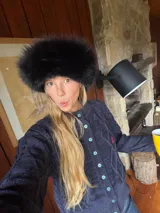 Saco tejido de punto con diseño de ochos y trenzas, color azul marino. Presenta cierre frontal con botones en contraste de color turquesa y un delicado bordado a mano en el pecho.