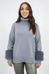 Polerón de punto color gris con cuello alto y puños con detalle de piel sintética en tono más oscuro. Presenta un corte holgado y diseño clásico.