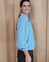 Camisa de jean azul con mangas largas abullonadas, puños ajustados y cuello clásico.