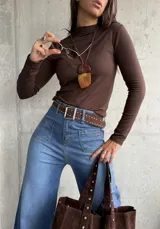 Polera de cuello alto y manga larga, confeccionada en tejido elástico color chocolate.