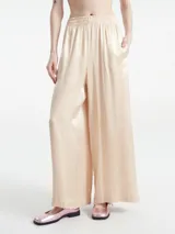Pantalón color beige claro a rayas verticales, de corte palazzo, con bolsillos laterales y cintura elastizada.