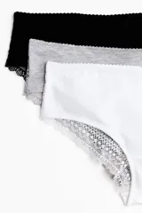 Pack de tres bombachas estilo hipster confeccionadas en punto de algodón con detalles de encaje en los bordes. El set incluye una prenda en color negro, una en blanco y una en gris melange. Cuentan con cintura estándar, refuerzo interior y cobertura media.