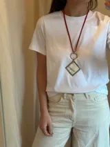 Collar largo con doble tiento de cuero rojo, aro metálico plateado y dije colgante de guampa engarzado en alpaca.