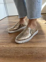 Zapatillas de cuero negro con diseño entretejido y suela blanca.