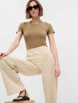 Jean de tiro alto con corte recto y holgado, en color beige claro. Presenta diseño clásico de cinco bolsillos, cierre frontal con botón y cremallera, y costuras reforzadas.