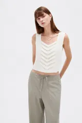 Musculosa sin mangas de color natural con cuello cuadrado y detalles de pliegues frontales en forma de chevrón.