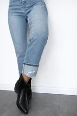 Pantalón de jean corte regular fit en color celeste claro. Presenta un diseño con pequeñas roturas frontales y botamanga con doblez, confeccionado en denim con elastano para mayor flexibilidad y comodidad.