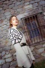 Saco tejido de punto con diseño de guarda inca en la parte superior. Presenta bolsillos frontales con detalles de tiras de cuero y flecos. De corte recto y largo medio, con terminaciones en tejido acanalado.