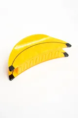 Broche para el pelo en forma de banana, color amarillo con detalles en negro, fabricado en acetato.