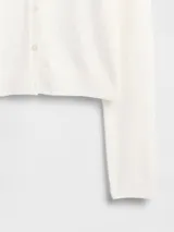 Saco de punto fino color marfil, con cuello redondo, cierre frontal con botones y mangas largas.