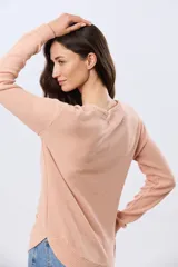 Buzo tejido liso de manga larga con cuello redondo, confeccionado en algodón de tejido grueso. Presenta bordes acanalados en el cuello, los puños y la cintura, con un pequeño detalle de placa metálica en el lateral inferior.