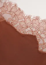 Vestido midi asimétrico de tejido satinado en color tostado, con un tirante fino y otro hombro descubierto. Cuenta con delicados ribetes de encaje a tono en el escote y en el bajo, y una sutil abertura lateral.