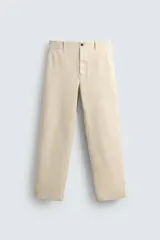 Pantalón chino regular fit de color beige, confeccionado en tejido de algodón. Cuenta con bolsillos frontales, detalle de bolsillo cerillero, bolsillos traseros de doble vivo y cierre frontal con cremallera y botón.