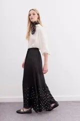 Pantalón amplio de viscosa y modal, color negro, con cintura elastizada y lentejuelas doradas aplicadas en la parte inferior de las botamangas.