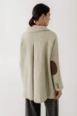 Blazer de corte recto y holgado en color beige con textura de espiga. Presenta solapas clásicas, cierre frontal con un botón central y bolsillos laterales con solapa.