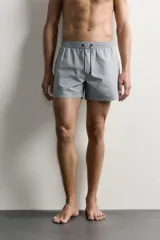 Short de baño confeccionado en tejido técnico con patrón de rayas verticales en tonos azul marino y blanco, con cintura elástica ajustable mediante cordón y bolsillos laterales.