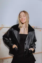 Campera bomber de cuero ovino negro con cuello de napalan negro, forrada y con detalles en cuero marrón desgastado con pasamanería y botones de guampa.
