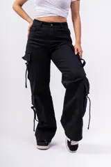 Pantalón cargo negro de jeans sin lycra, corte holgado y tiro alto. Cuenta con múltiples bolsillos laterales con solapa y cordones ajustables.