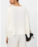 Top fluido satinado color marfil, con línea rectangular, cuello pañuelo que gira desde el delantero hacia la espalda sujeto con hebilla decorativa dorada en el hombro izquierdo y manga larga con dos botones en el puño.