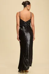 Vestido largo de fiesta color negro con acabado metalizado y diseño plisado en toda la prenda. Presenta breteles finos, escote redondo y un detalle de fruncido central que crea un efecto visual dinámico en la silueta.