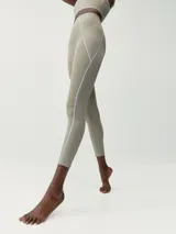 Legging largo deportivo color beige, confeccionado en tejido Shape_Tech. Presenta costuras decorativas en contraste de color celeste claro que recorren las piernas y un pequeño bolsillo lateral.