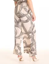 Conjunto de dos piezas compuesto por una camisa de cuello solapa con escote en V y mangas cortas con trabilla, y un pantalón estilo palazzo de tiro alto con cintura elástica y bolsillos laterales. Ambas prendas presentan un estampado geométrico lineal en tonos neutros y se complementan con un cordón trenzado para ajustar la cintura.