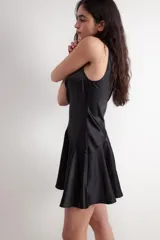 Vestido corto negro de acabado satinado tipo gloss, sin mangas, con escote drapeado y falda evasé con corte asimétrico.
