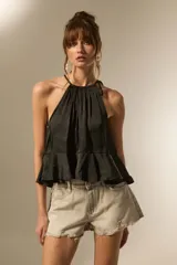 Top negro de cuello halter con frunces, diseño holgado y corte cropped con volado en el ruedo.