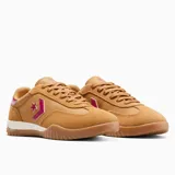 Championes Converse Run Star Trainer Ox color mostaza, con detalles en fucsia y blanco. Presentan el logo de la estrella y el chevrón en fucsia en el lateral, y suela de goma con diseño ondulado.