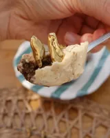 Anillo de diseño orgánico y macizo con forma irregular, elaborado en metal con acabado brillante. Presenta una estructura abierta que permite su ajuste.