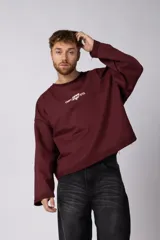 Buzo de cuello redondo con diseño boxy y acabado rústico al corte. Presenta costuras visibles y estampados en el frente, la espalda y el interior, permitiendo un uso reversible.