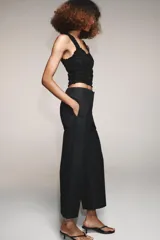 Pantalón marrón de tiro alto con bolsillos delanteros y traseros. El bajo está acabado con vuelta. Cierre frontal con cremallera y ganchos metálicos.