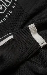 Sweater de punto negro con cuello redondo, mangas largas con franjas laterales blancas y puños en punto rib. Presenta un diseño gráfico bordado en el pecho con la inscripción 'RAVERS' y detalles en blanco.