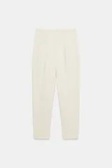 Pantalón de tiro alto y corte slim fit, de largo tobillero, color beige claro con costuras marcadas en la parte delantera.