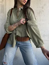 Camisa de manga larga color verde militar con inserciones de encaje decorativo en el frente y las mangas, cuello camisero y cierre frontal de botones.