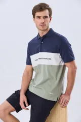 Remera polo de manga corta con diseño en bloques de color en tonos azul marino, blanco y verde militar, con bordado frontal y cierre de botones.