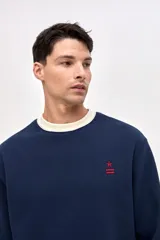 Buzo de cuello redondo en felpa con friza, color azul marino con detalle de cuello en color crema. Presenta bordado de la marca en el pecho y en el puño de la manga.