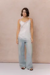 Musculosa de satén color crema con breteles finos regulables, escote en V y detalles de encaje en el escote, en diagonal sobre el delantero y en el ruedo.