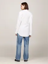 Camisa blanca de algodón orgánico, corte regular entallado, cuello inglés, mangas largas con puño, bajo más largo en la parte trasera y logo TH bordado en el pecho.