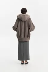 Chaqueta amplia de silueta balloon en color gris, con capucha integrada y solapa interior revestida en piel sintética tipo peluche. Presenta mangas largas con puños elásticos y un diseño envolvente y relajado.