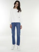 Pantalón jean azul de corte recto, con terminación desflecada y botones dorados en el ruedo.