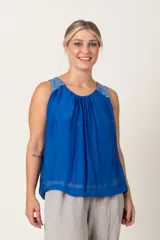 Blusa sin mangas de seda color azul con detalle de bordado plateado en los hombros.