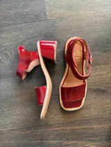 Sandalias de cuero color cereza, con tira ancha sobre los dedos, tira con hebilla al tobillo y taco cuadrado de madera.