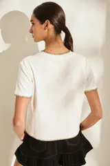 Remera marrón de manga corta y cuello redondo, con detalles de costuras decorativas en contraste color crudo en el cuello, los puños y el dobladillo inferior. Cuenta con el nombre de la marca impreso en el pecho.