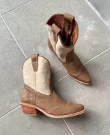 Botas estilo tejano de cuero vacuno en combinación de colores tostado y beige, con costuras decorativas en contraste y taco bajo de madera.