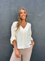 Sobrecamisa de viscosa con detalles de lúrex, color marfil, con escote en V, cierre frontal abotonado y mangas abullonadas.