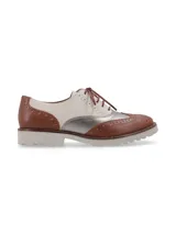 Zapato Oxford de cuero color cognac, blanco y plateado, con cordones marrones, detalles de perforaciones y suela de goma blanca.