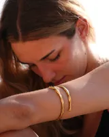 Brazalete rígido de diseño minimalista con forma de espiral, elaborado artesanalmente en bronce y alpaca maciza. Es una pieza ajustable que puede lucirse tanto en el antebrazo como en la parte superior del brazo.