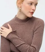 Blusa de chenille color beige, con cuello alto y diseño ajustado al cuerpo. Presenta mangas largas y una textura acanalada en toda la prenda.