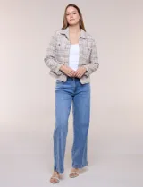 Chaqueta confeccionada en tejido de tweed beige con trama estructurada. Presenta cuello con solapa, frente abierto con botones metálicos y cuatro bolsillos funcionales. Las mangas largas de calce recto cuentan con bocamangas decoradas con botones y terminaciones deshilachadas al igual que los bordes.